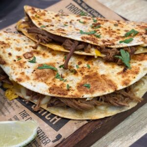 Mouth-watering beef quesadillas garnished with cilantro and served with a lime wedge.