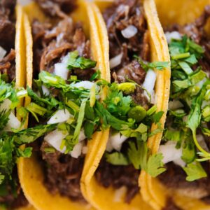 Close-up of delicious beef tacos topped with fresh cilantro and onions, perfect for Mexican cuisine lovers.